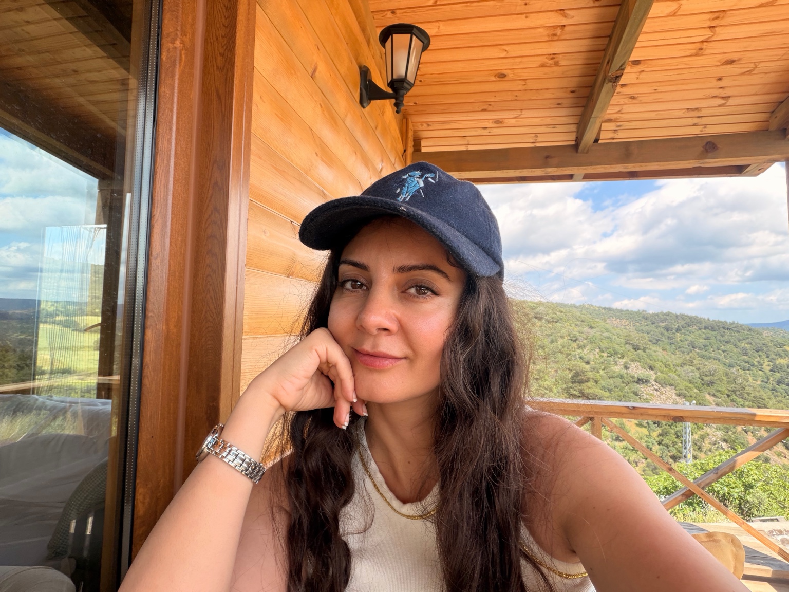 Dilara sitting on a wooden veranda overlooking a green landscape