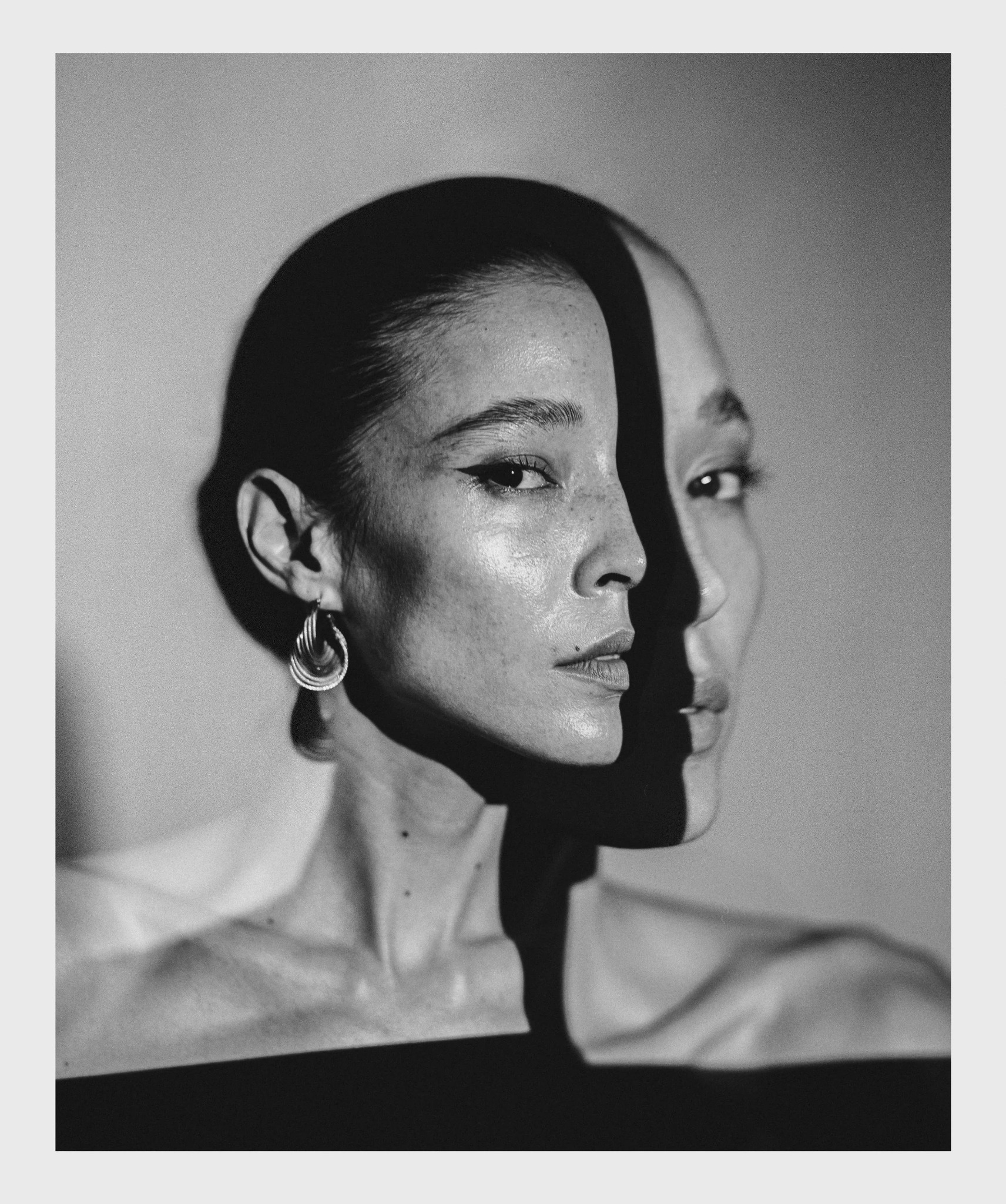 Black and white editorial portrait of a woman with a shadowed double profile, symbolizing the parts of the self kept hidden
